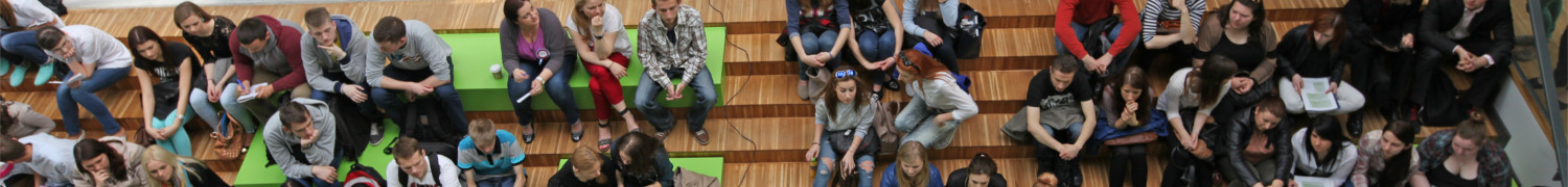 Duża grupa ludzi na siedzi na drewnianych schodach na forum akademickiej 1