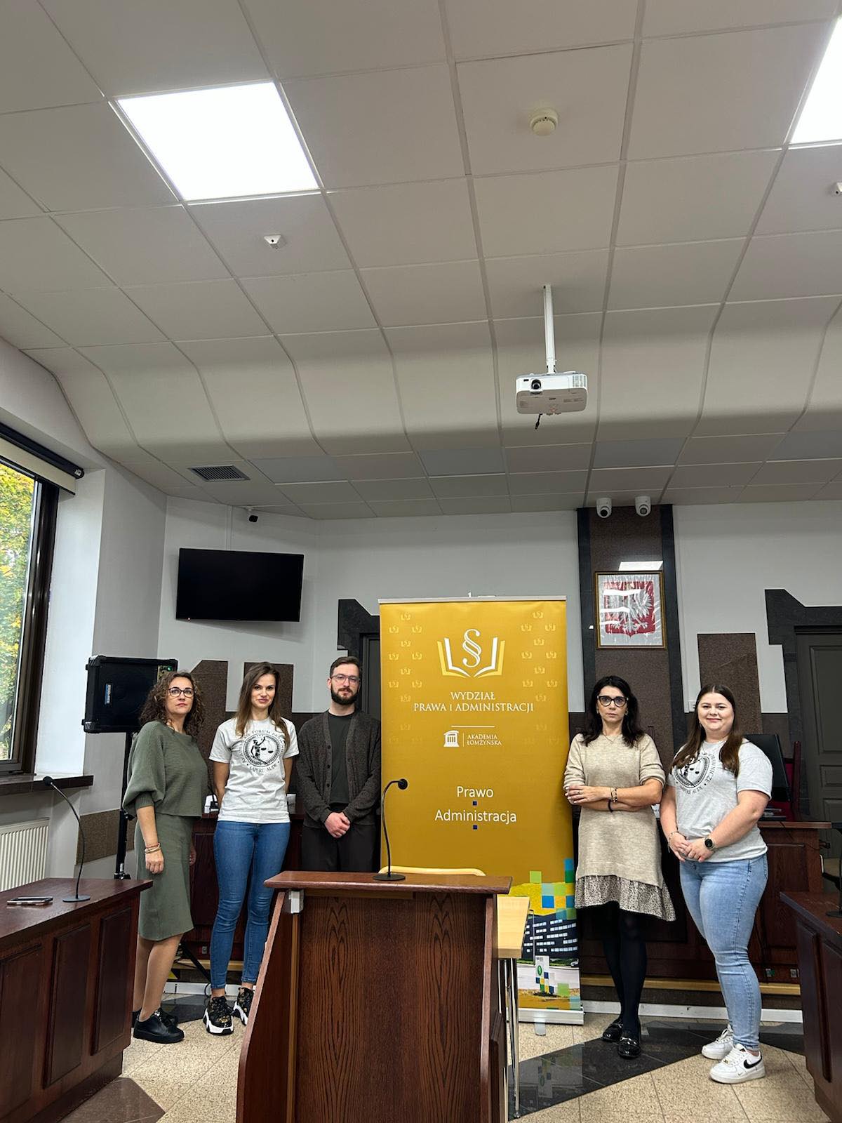 kilka osób w sali rozpraw sądowych pozuje do zdjęcia