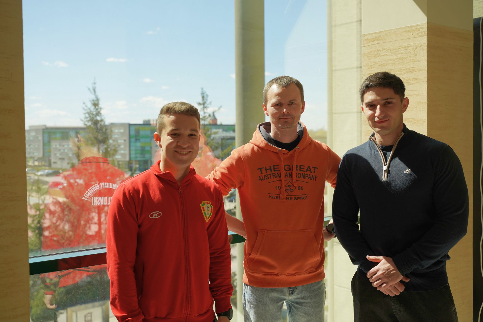 Three men in front of a glass wall