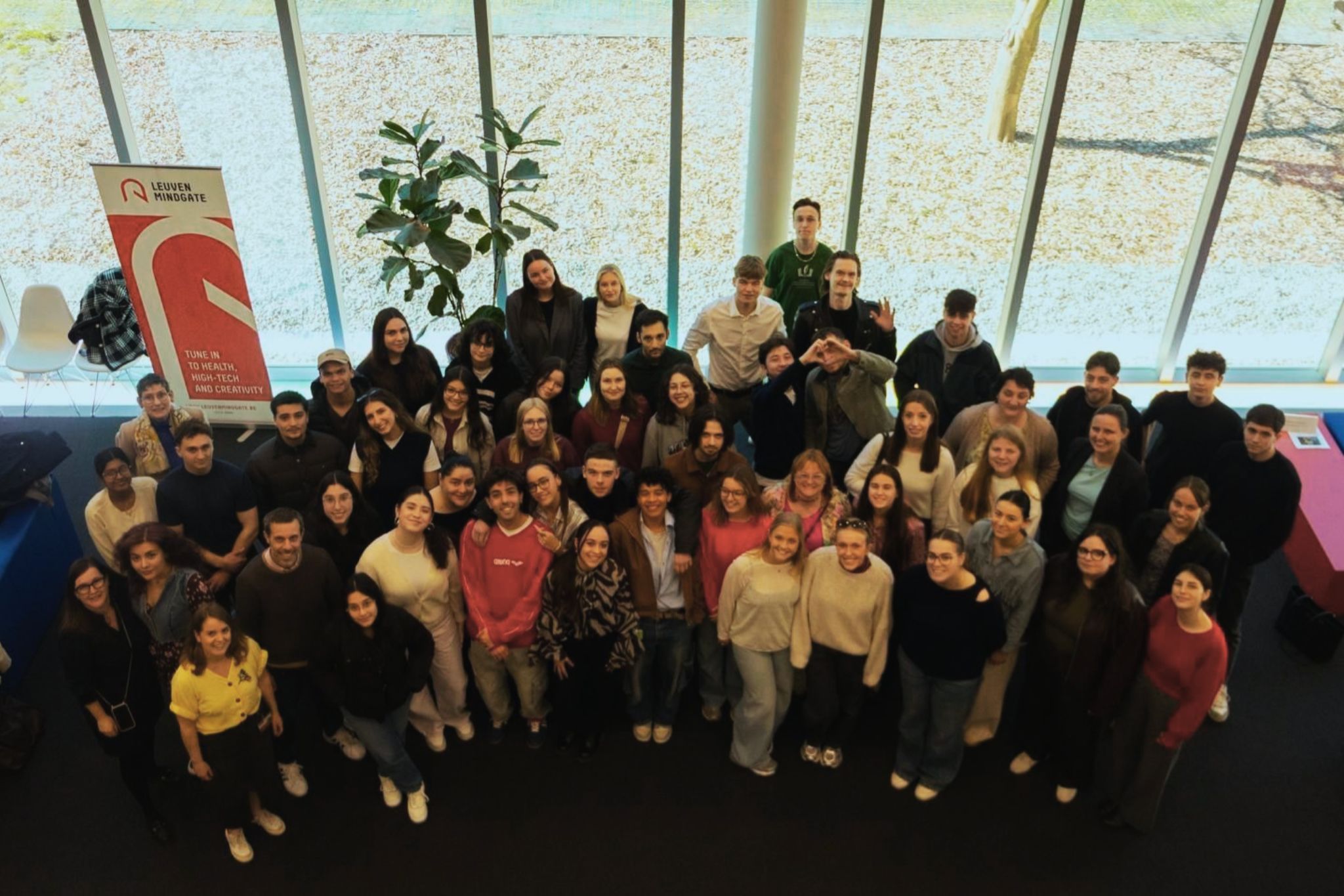Grupa studentów spogląda na fotografa, który wykonuje zdjęcie z wysokości balkonu/piętra