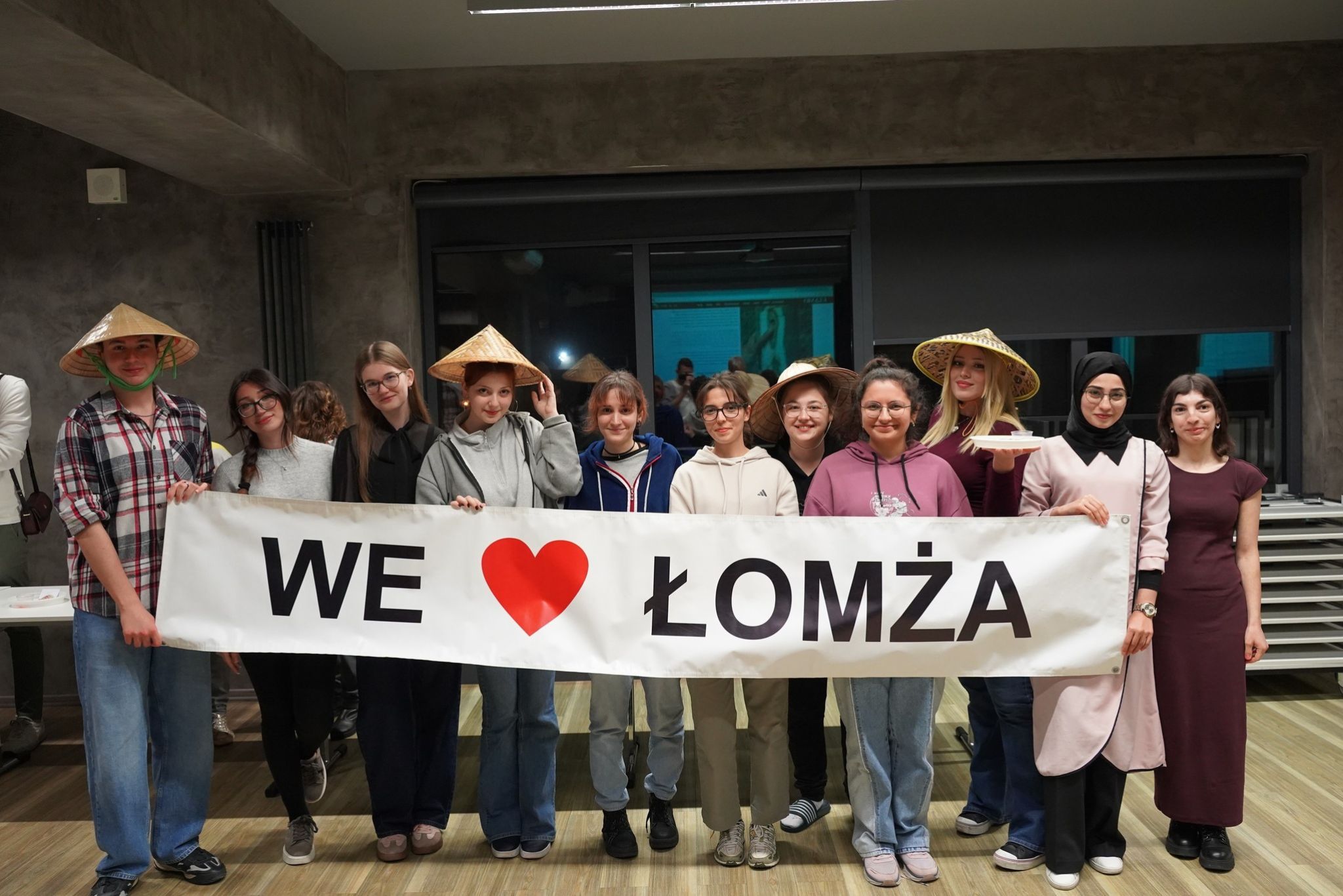 Grupa studentów w budynku pozuje do zdjęcia trzymając baner z napisem I love Łomża