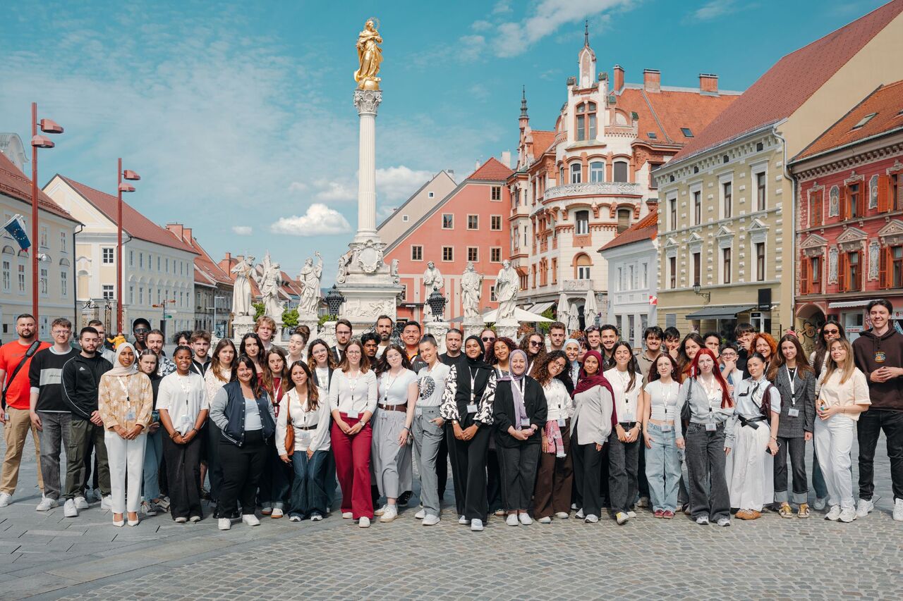 Grupa studentów pozuje na tle starego rynku w Mairborze