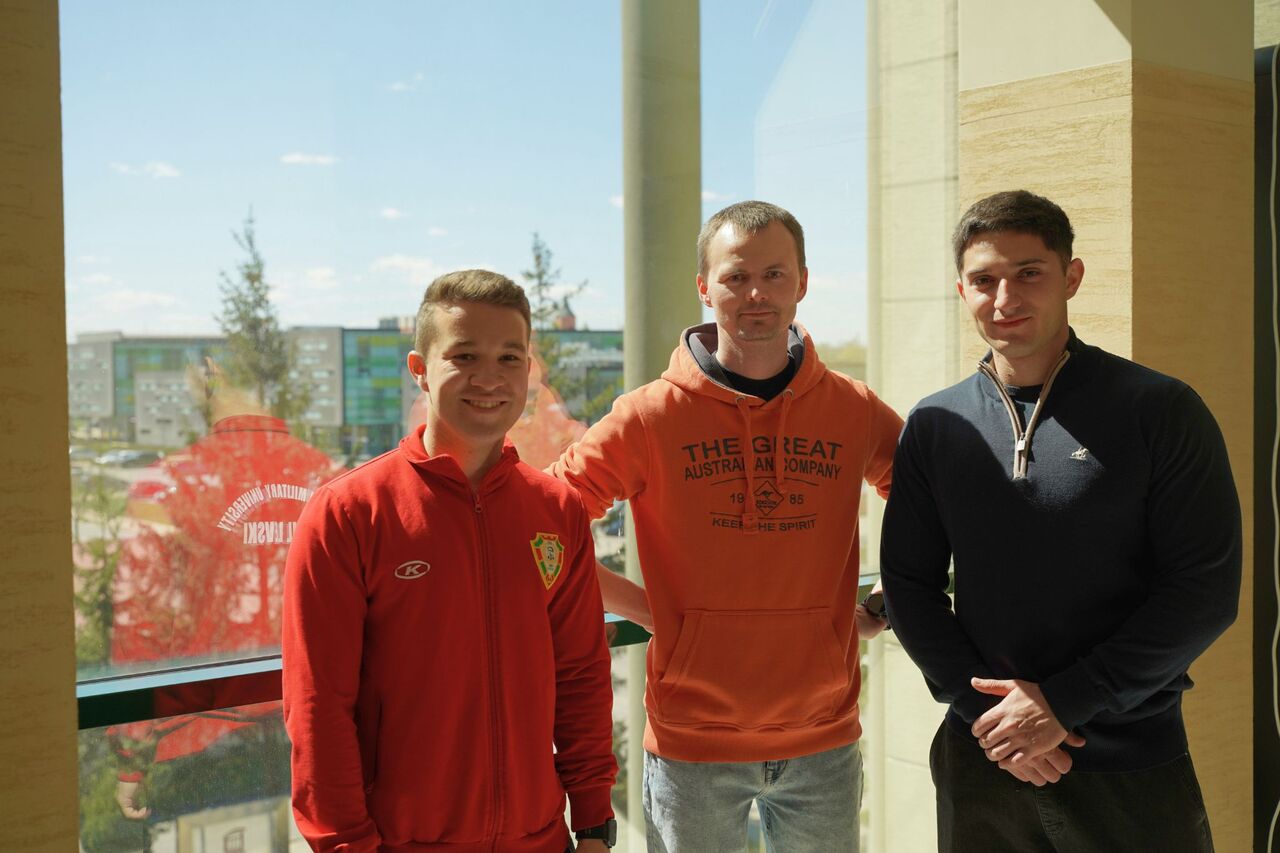 Three men in front of a glass wall