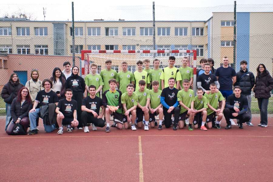 Grupa ludzi w sportowych ciuchach pozuje do zdjęcia na boisku