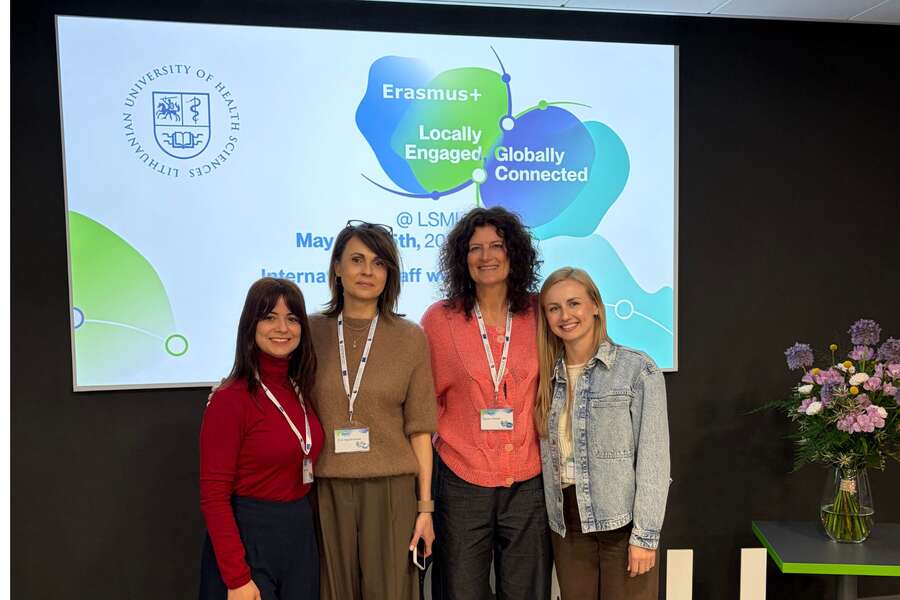 A group of four women posing for a photo in front of a presentation.