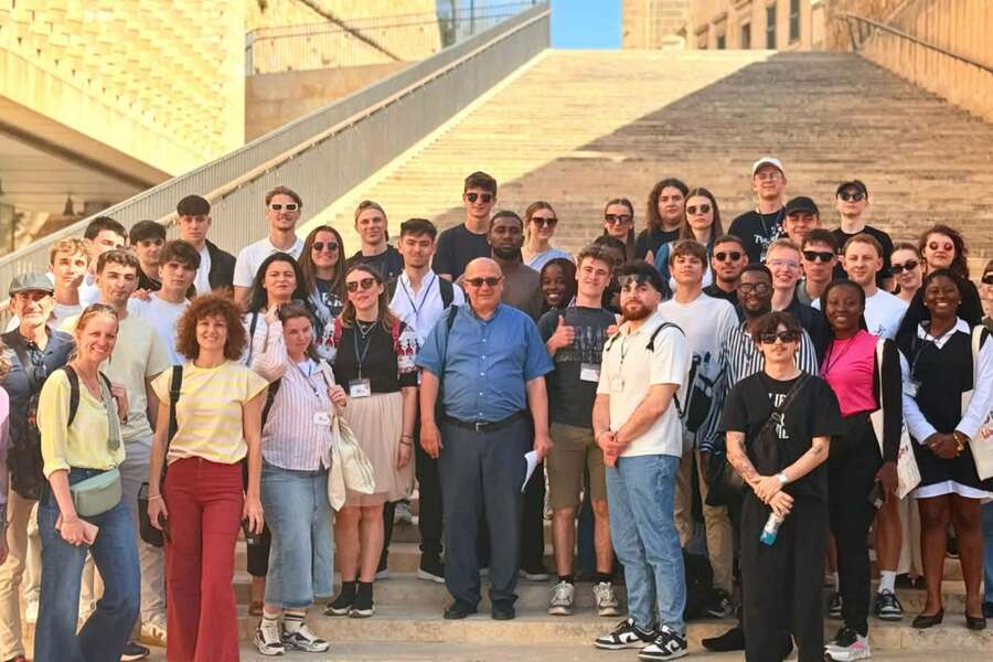 A group of people posing for a photo in front of sand-colored steps.