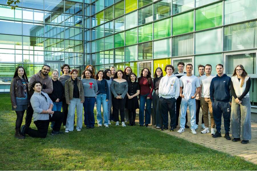 Grupa studentów pozuje do zdjęcia na tle szklanego budynku