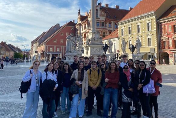 Grupa osób pozuje do zdjęcia na tle starego rynku Mariboru