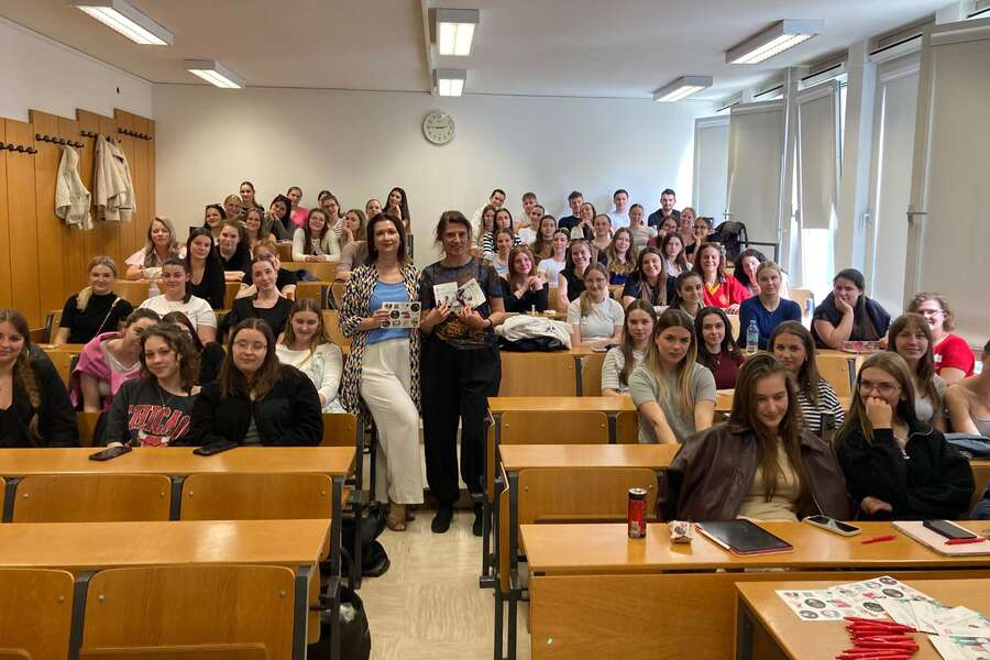 Two lecturers are standing in the middle of the room, surrounded by a large group of students