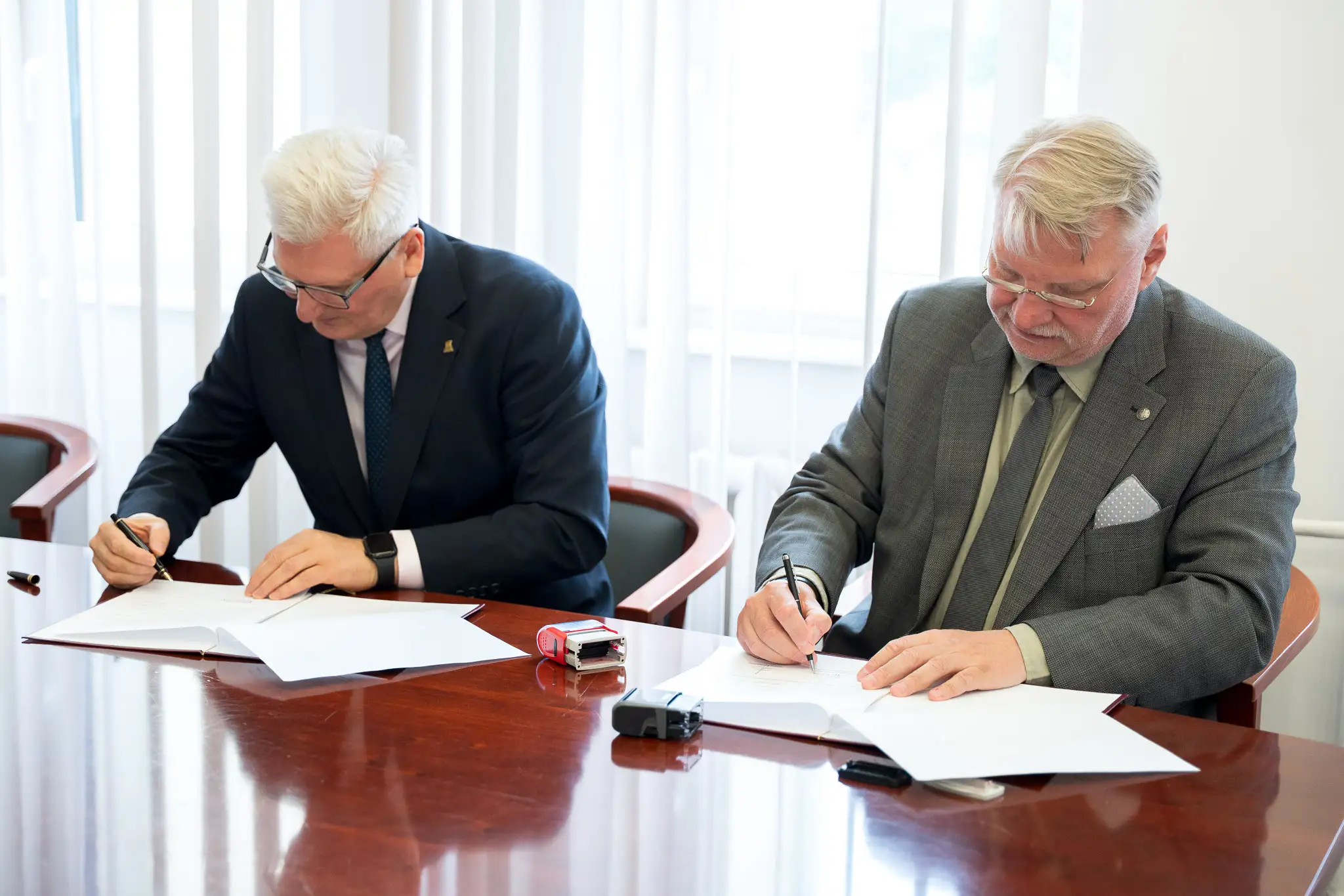 dwie osoby podpisują porozumienie przy stole