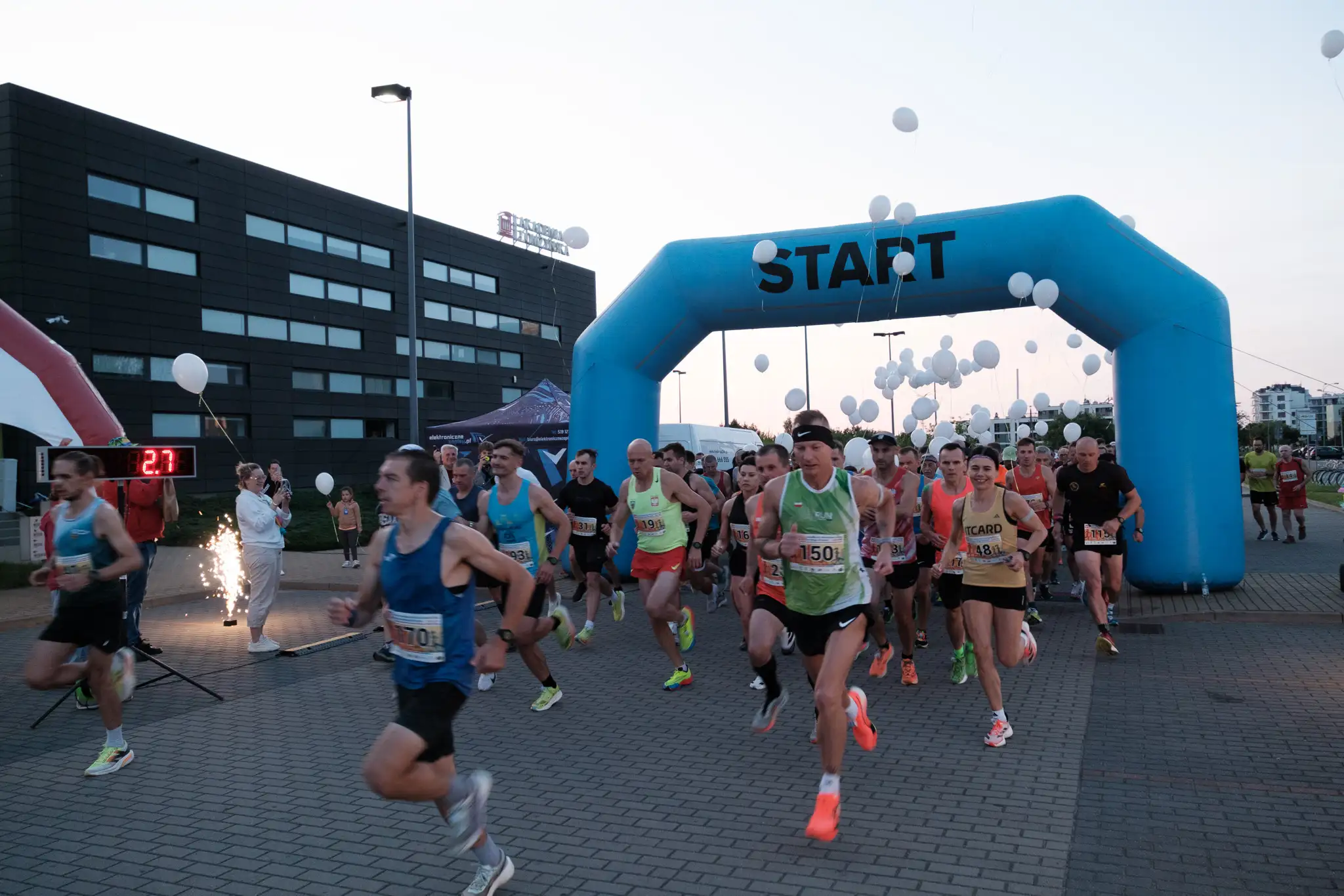 biegacze startują na akademickiej, w tle balony i budynek uczelni