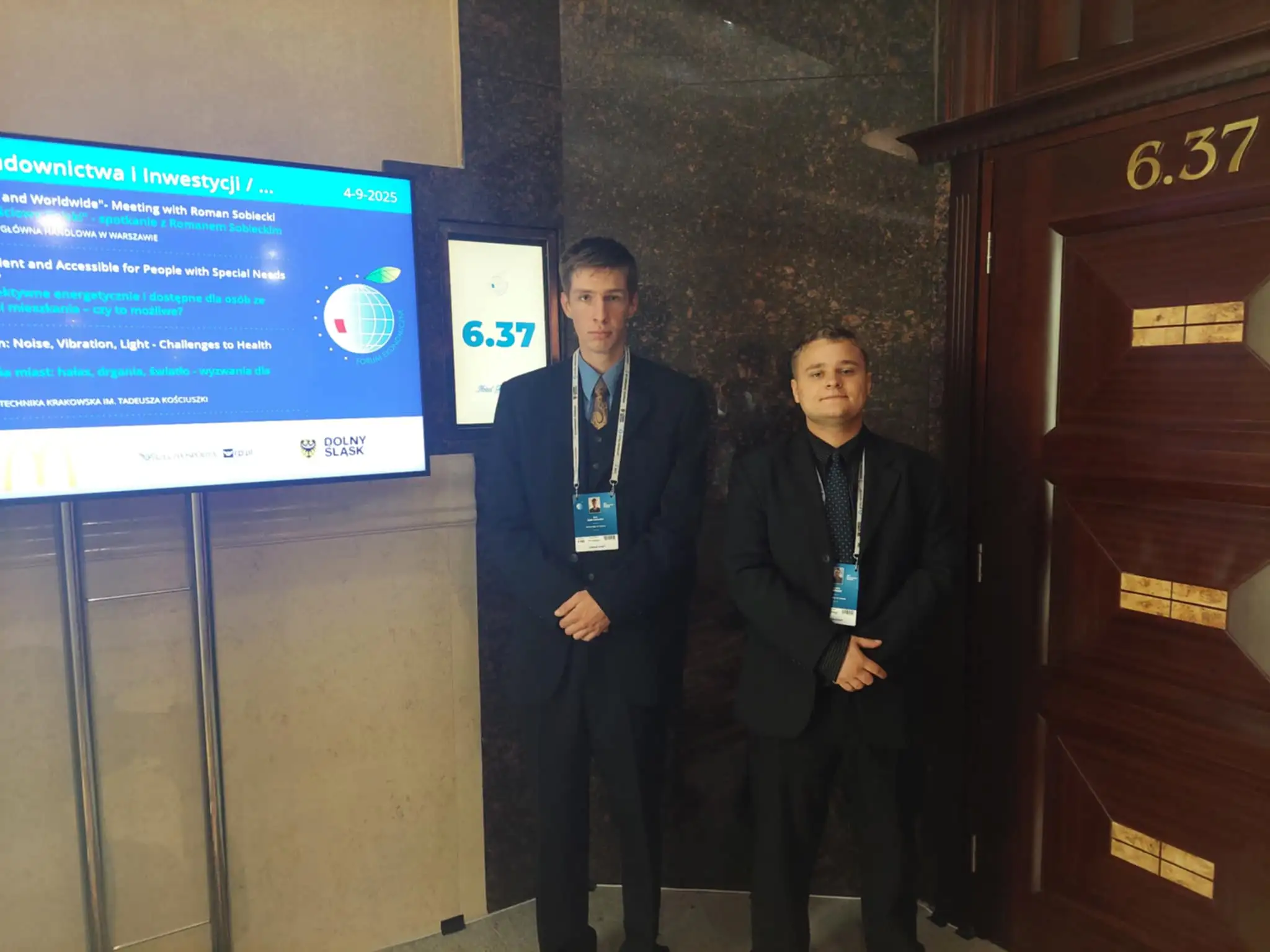 dwie osoby w garniturach pozują do zdjęcia 