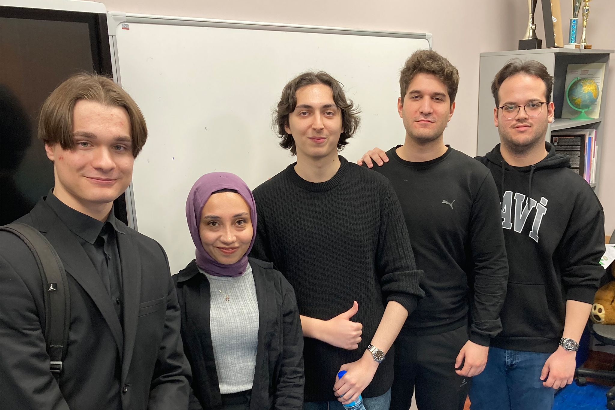 Grupa sześciu osób stoi obok siebie w sali dydaktycznej, pozując do wspólnego zdjęcia na tle tablicy.