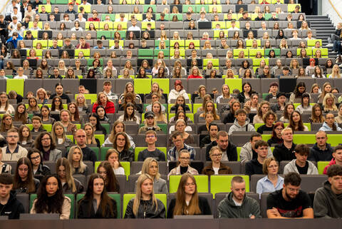 duża grupa studentów na siedzi na auli