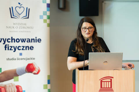 osoba przy mównicy w tle baner wychowania fizycznego