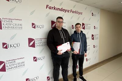 Studenci Damian Olszewski, Arkadiusz Gardocki w Turci na tle ścianki reklamowej trzymają dokumenty