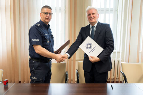 dwie osoby uściskują sobie dłoń, w rękach trzymają porozumienie