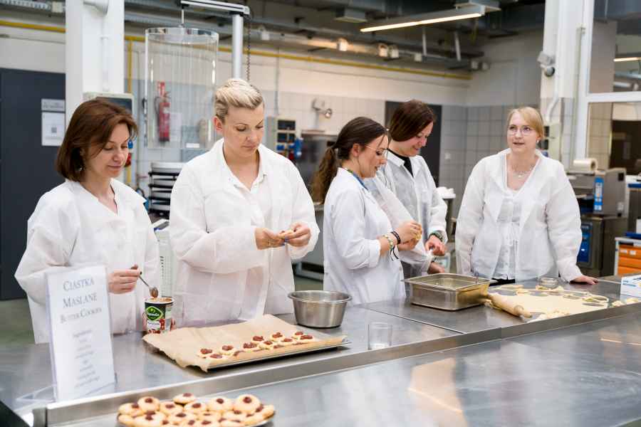 Kobiety ubrane w białe fartuchy robiące ciasteczka