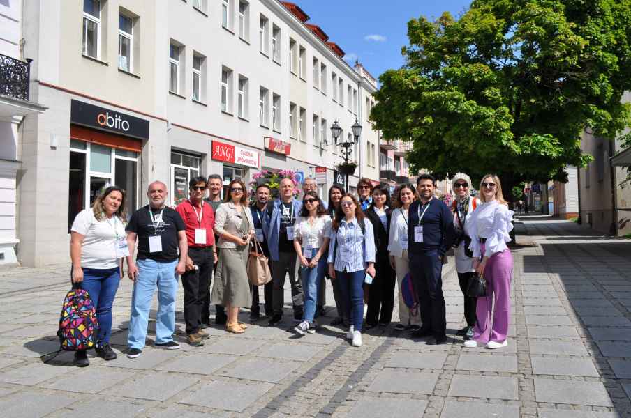 Grupa osób na tle budynków starego rynku w Łomży