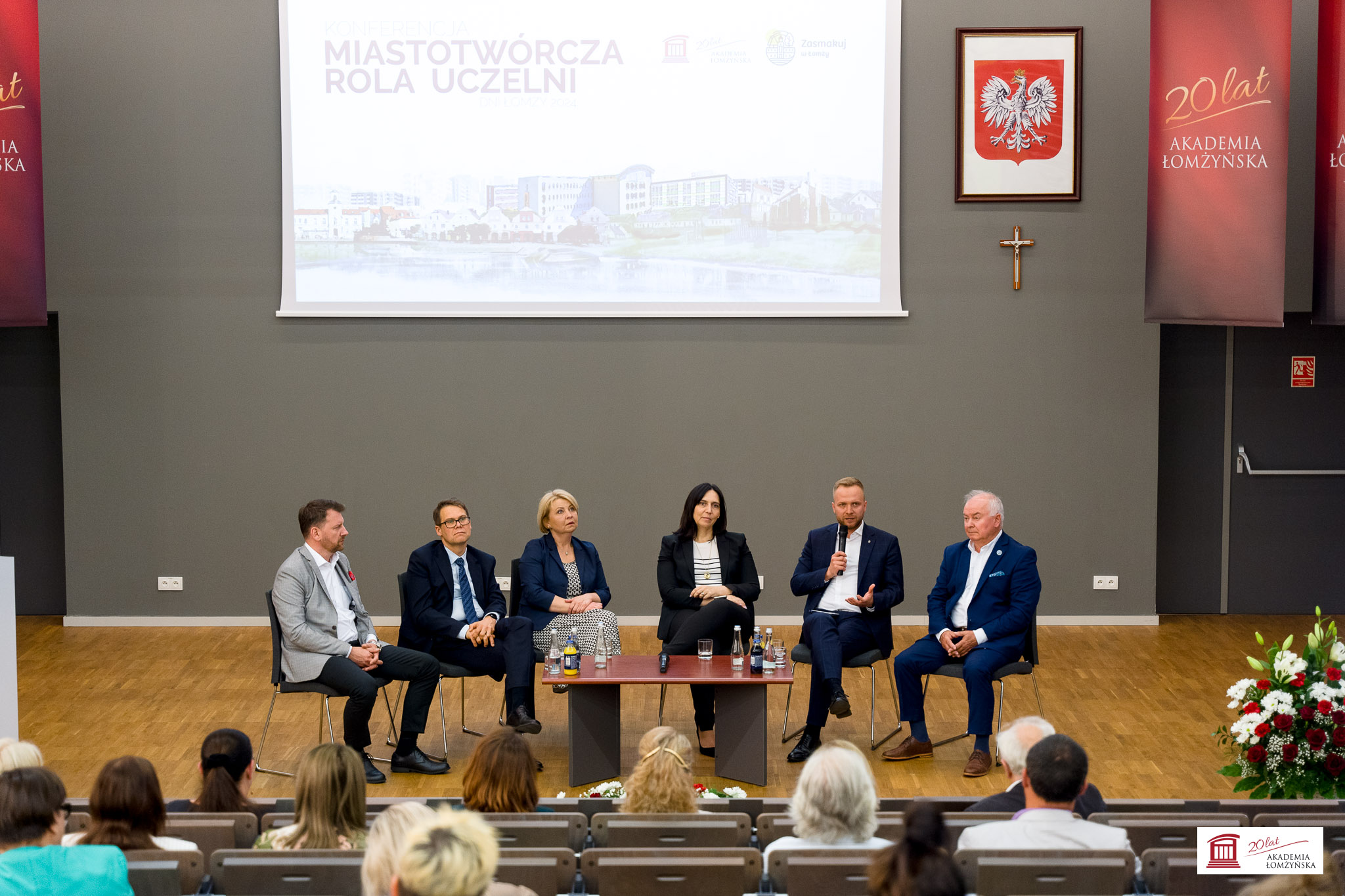 prelegenci siedzą przy stole na scenie auli