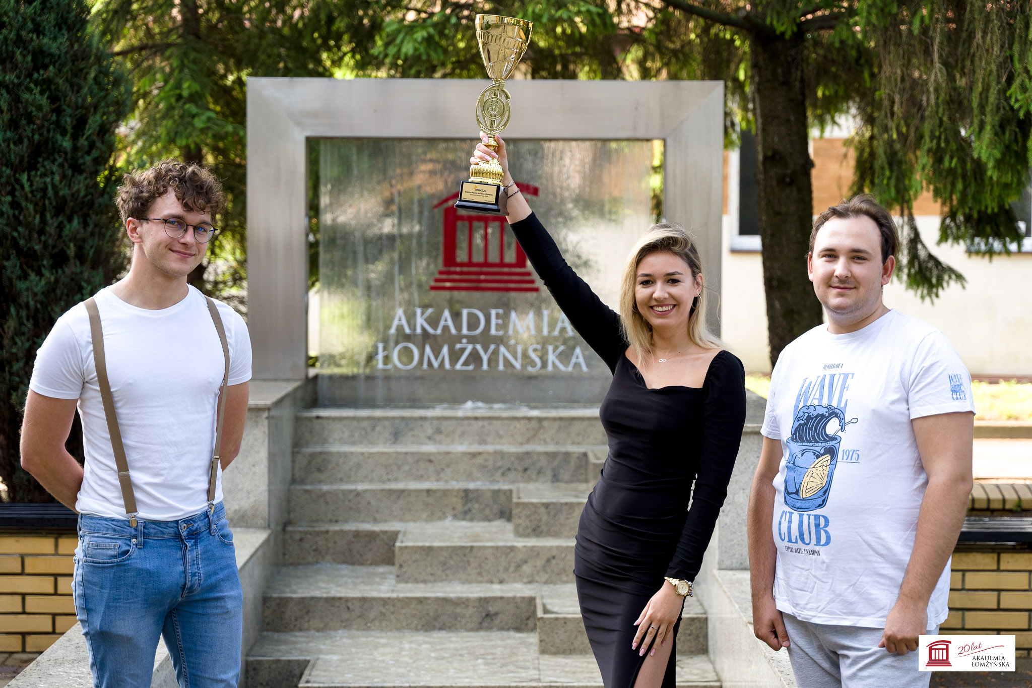 Troje studentów pozuje przed fontanną z pucharem za zajęcie trzeciego miejsca