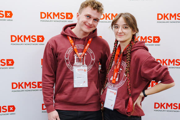 dwoje studentów: Piotr i Ania na tle ścianki reklamowej DKMS