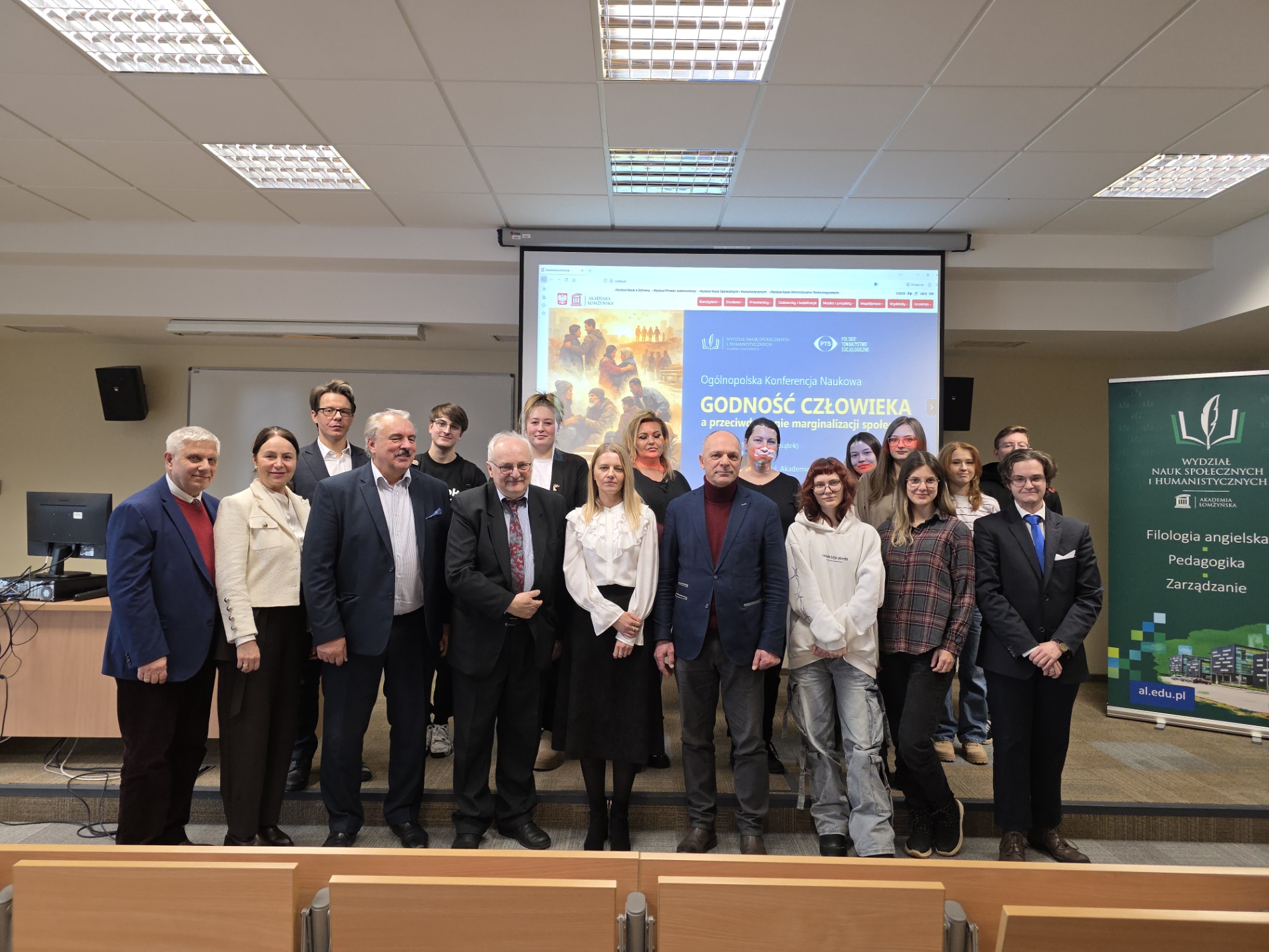 Organizatorzy i prelegenci konferencji pozują do zdjęcia grupowego. W tle baner z tytułem konferencji