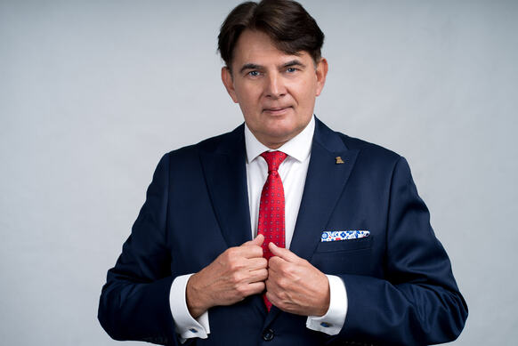 dr Jacek Szymański w garniturze patrzy na wprost