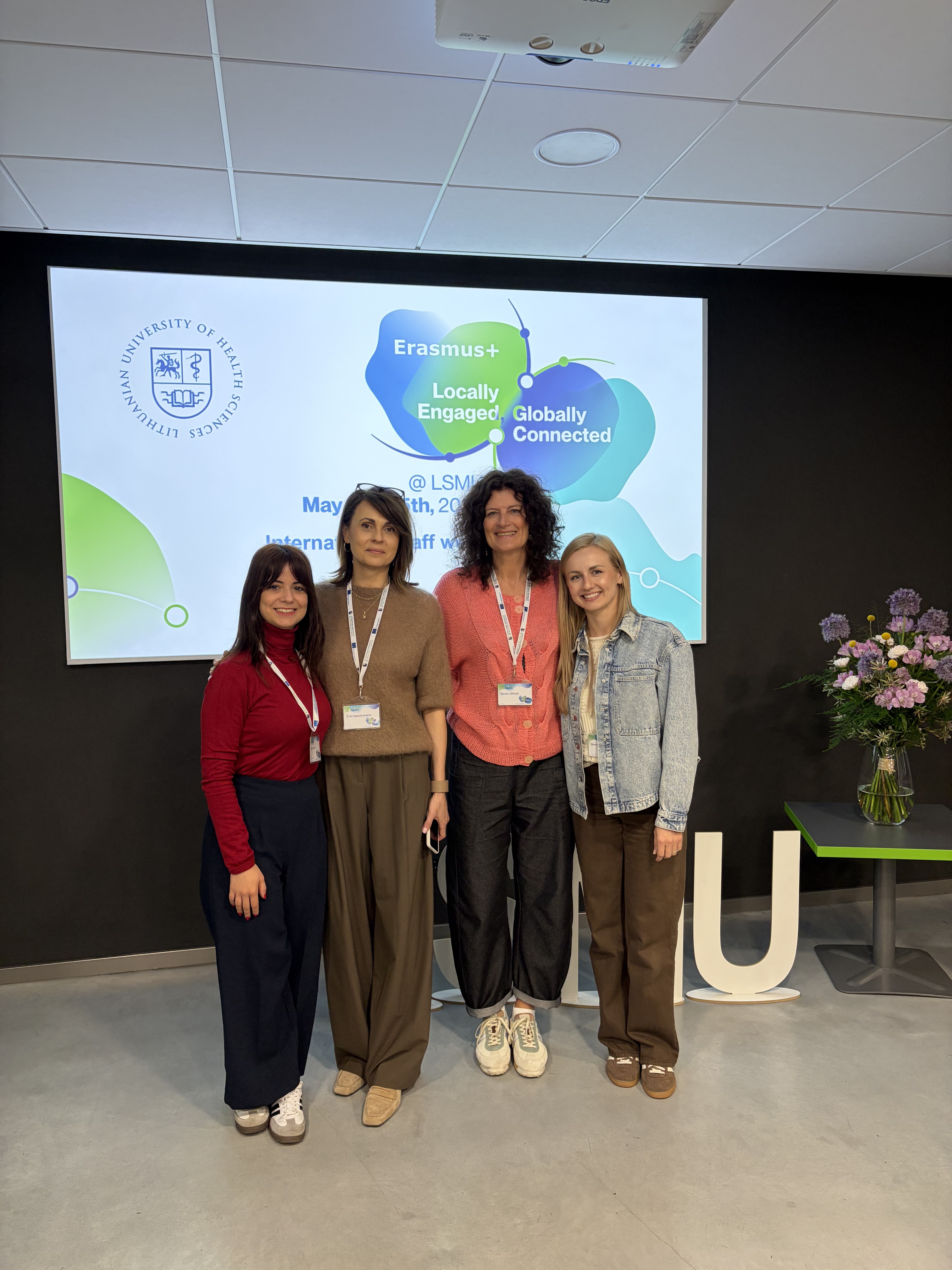 Grupa czterech uczestników International Staff Week Erasmus+ stojąca przed ekranem z prezentacją Lithuanian University of Health Sciences w Kownie (maj 2026).
