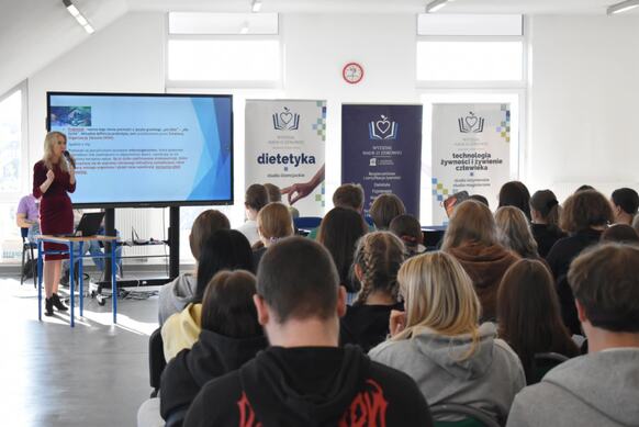 Zdjęcie przedstawia dużą grupę uczniów siedzących w dużej sali podczas wykładu o zdrowym stylu życia