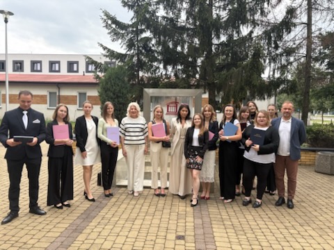 Na tle fotofontanny przy budynku Akademii Łomżyńskiej, komisja dyplomowania wraz ze studentami po obronie prac dyplomowych
