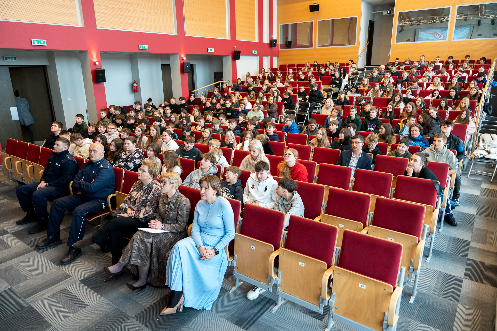 Aula wykładowa zapełniona osobami siedzącymi na krzesłach.
