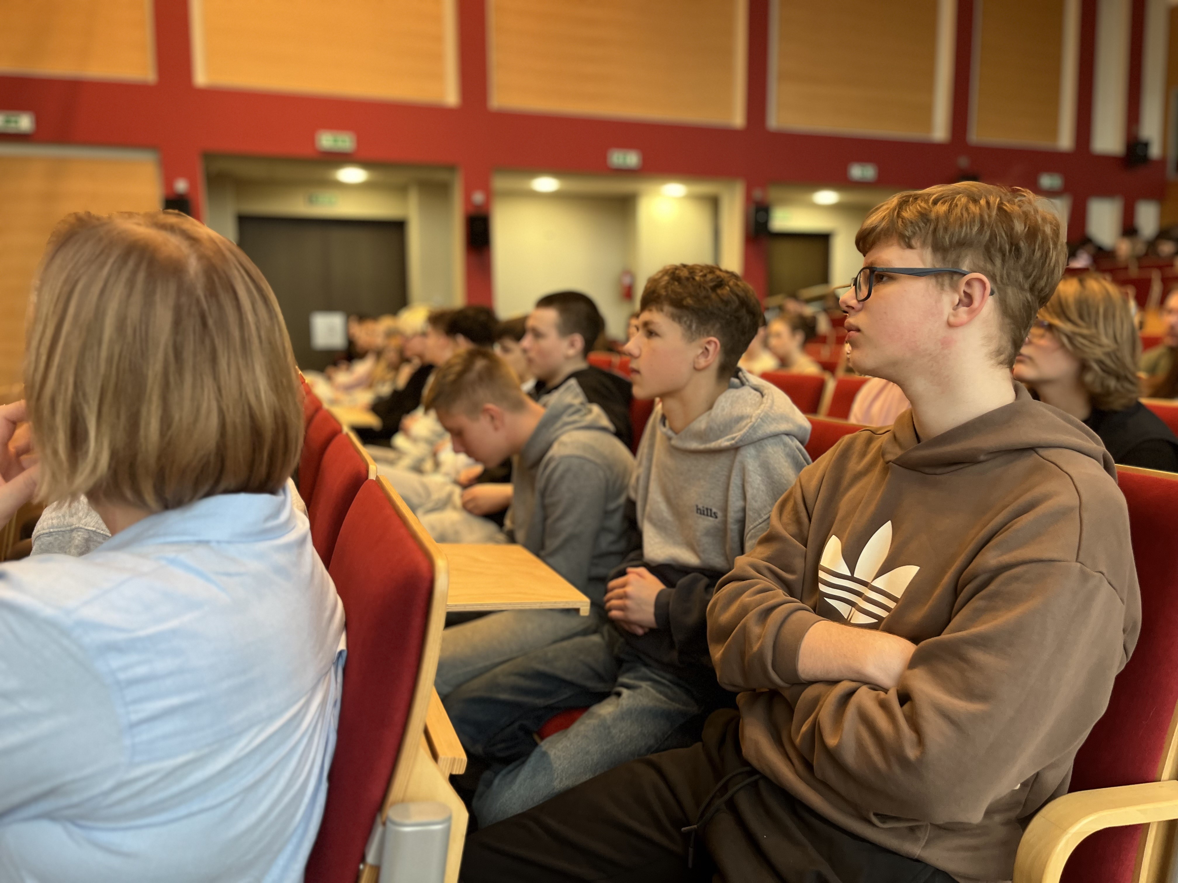 Grupa osób siedzi na auli uważnie słuchając.