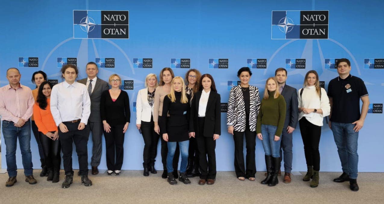 Grupa osób na tle ścianki NATO