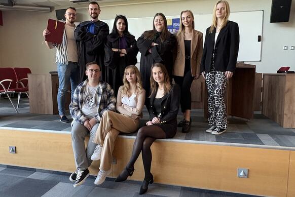 Studenci odgrywajacy symulację rozprawy sądowej wraz z opiekunem wydarzenia.