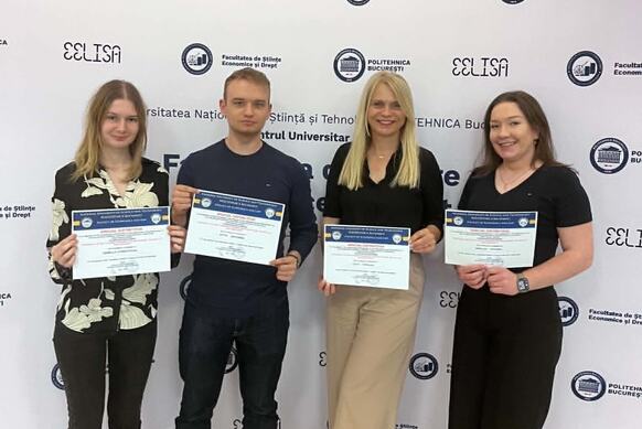 Trzy kobiety i mężczyzna pozują do zdjęcia trzymając w ręku dyplomy.